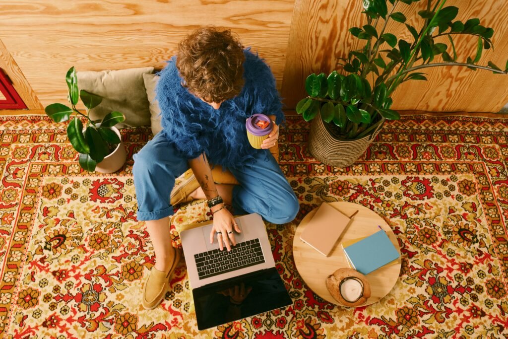 Person working on laptop surrounded by notes and coffee at home