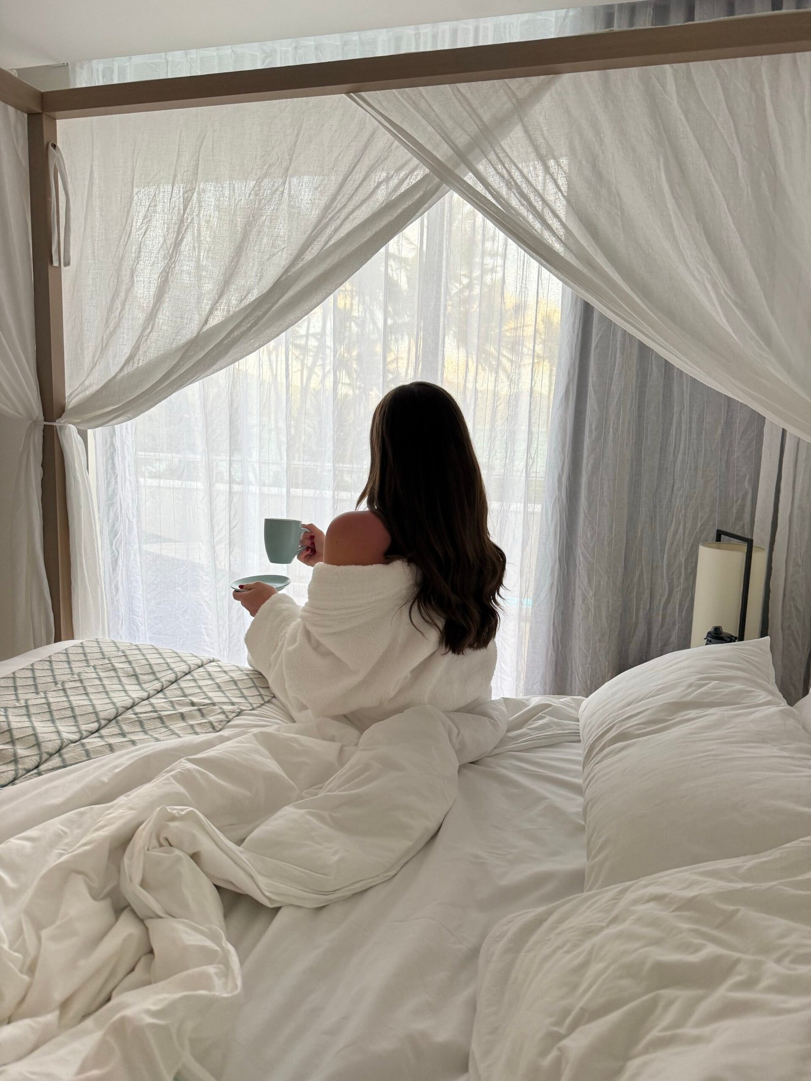 Woman sitting on bed in the morning drinking coffee